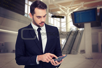 Composite image of concentrated businessman in suit using calculator