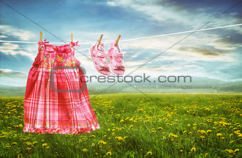 Dress and sandals on clothesline in fields of dandelions