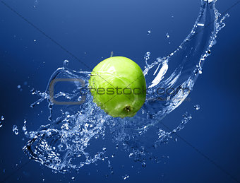 Green apple with water splash, on blue water