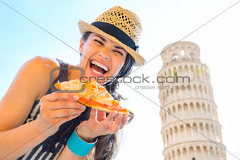 Laughing woman tourist holding slice of pizza in Pisa