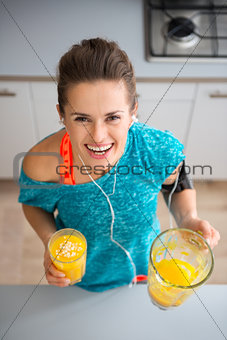 Athletic smiling woman holding freshly-made smoothie in kitchen