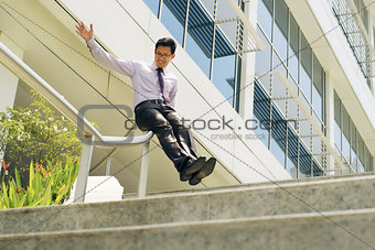 Chinese Businessman Going Downstairs Sliding On Rail For Joy