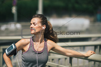 Woman runner taking a break in the sunshine listening to music