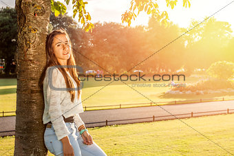 Beautiful teenager leaning on a tree