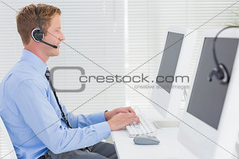 Handsome agent with headset typing on keyboard