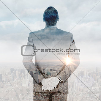 Composite image of young businessman standing with hands behind back