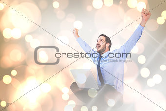 Composite image of excited cheering businessman sitting using his laptop