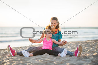 Smiling mother and daughter sitting together stretching arms out