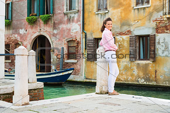 Woman looking back over shoulder smiling, standing near canal