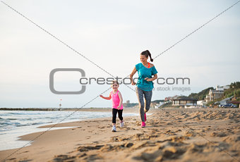 Mother and daughter running on the beach at sunset