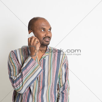 Mature casual Indian man talking on smartphone
