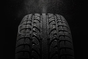 Tire with water drops over black background