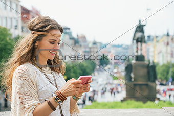 Longhaired bohemian young lady writing sms on mobile, Prague