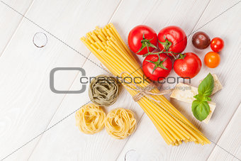 Pasta, tomatoes, basil on wooden table