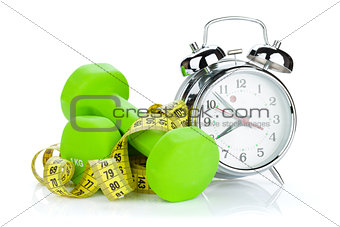 Two green dumbells, tape measure and alarm clock