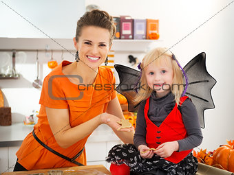 Girl in bat costume with mother holding Halloween cookies