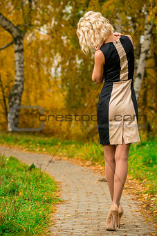 slim blonde walks alone in the park