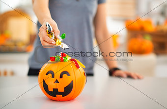 Woman putting trick or treat candy in halloween bucket. Closeup
