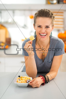Happy young woman in kitchen showing halloween boo chips treats