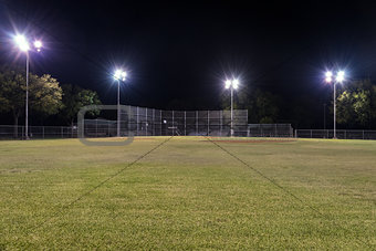 Empty baseball field at night with the lights on