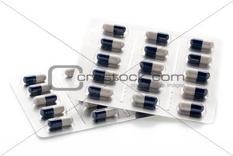 Dark blue and white capsules in medication blister packs.