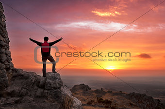 Man on top of a mountain victorious admiring the sunrise - 2