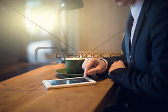 close up of hand using tablet computer at cafe