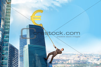 Businessman climbing skyscraper with euro sign