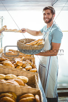 Portrait of happy worker holding basket of bread