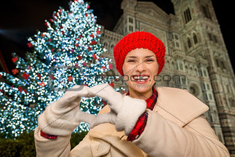 Woman showing heart shaped hands near Christmas tree in Florence
