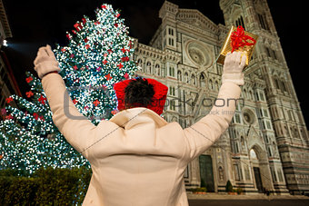 Woman with gift box rejoicing near Christmas tree in Florence