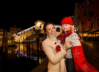 Mother and daughter pulling gift from Christmas sock in Venice