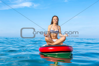 Woman relaxing over a paddle surfboard