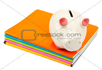 Piggy bank on pile of copybooks