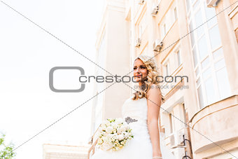 Beautiful bride in magnificent dress stands alone on stairs