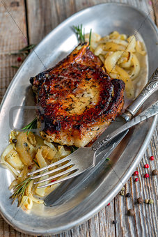 Pork chop with rosemary and fried onions.