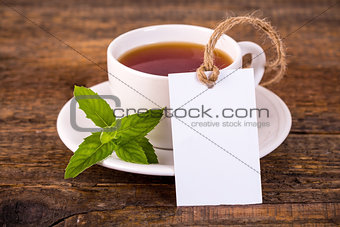 Cup of tea with green leaves and blank tag