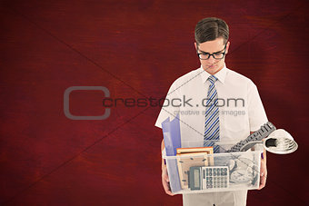 Composite image of fired businessman holding box of belongings
