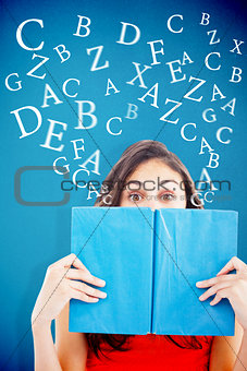 Composite image of portrait of a student hiding behind a blue book
