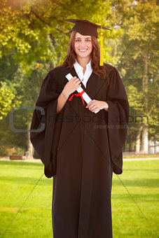 Composite image of full length shot of a graduate holding a degree and looking at the camera