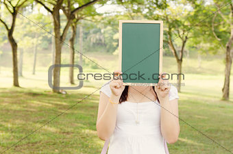 Asian female college student holding blank chalkboard