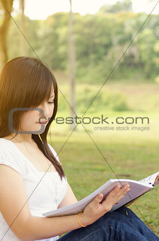 Young Asian college student reading book