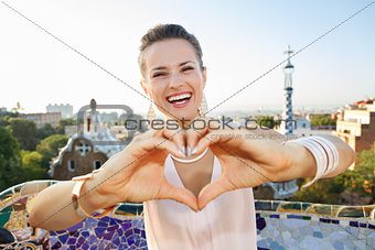 Woman tourist showing heart shaped hand in Park Guell, Barcelona