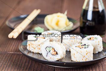 Uramaki sushi with carrot, cucumber, surimi and roasted white se