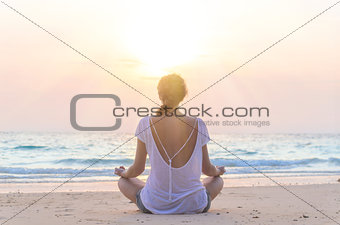 woman practicing yoga at sunrise beach