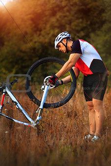 cyclist repairs bicycle on the meadow