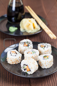 Uramaki sushi with carrot, cucumber, surimi and roasted white se