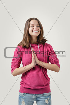 Happy girl standing straight holding her hands together as symbol of gratitude