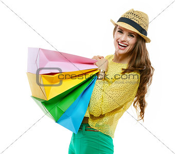 Woman in hat and bright clothes holding heavy shopping bags