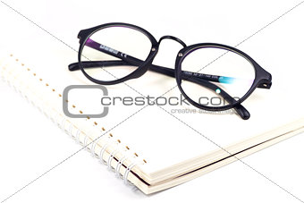 Blank spiral notebook and eyeglasses isolated on white backgroun